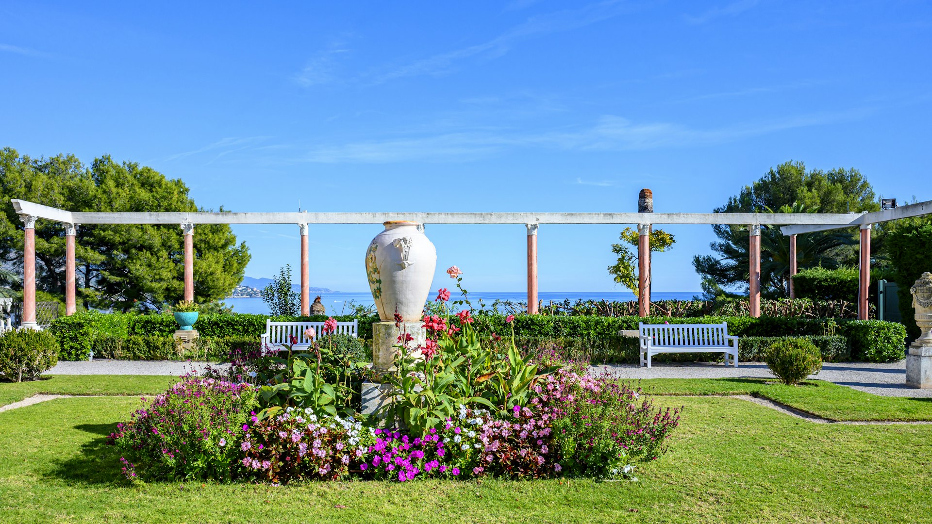 Jardín mediterráneo cuidado con césped, setos perfilados y vistas al mar en Mallorca